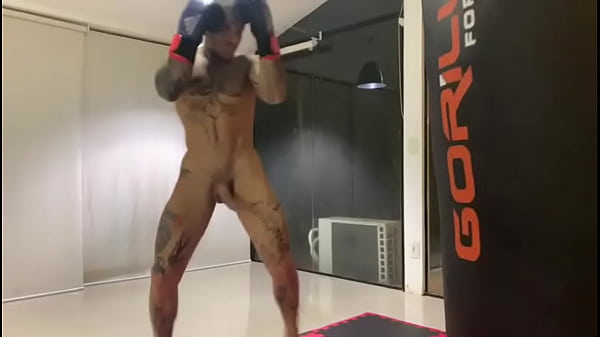 Boxeador dotado batendo no saco de pancada de pau duro