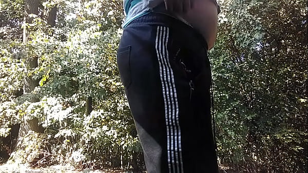 A young, pot-bellied guy peeing in the woods