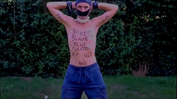 naked slave exposed in penis cage striptease on outdoor party with dirty body writing BDSM CBT